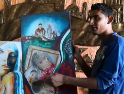 الشاب الرسام بجانب لوحاته الفنية