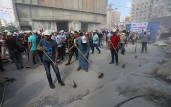 متطوعون فلسطينيون يزيلون أنقاض المباني التي دمرتها الغارات الإسرائيلية