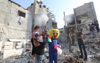 مهرجون من فوق ركام المنازل بمدينة رفح جنوب قطاع غزة يمارسون ألعابهم البهلوانية في محاولة للتخفيف عن الأطفال نفسيًا بعد العدوان الأخير