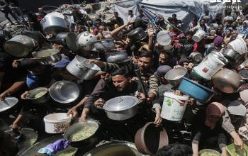 مواطنون من بينهم أطفال يتجمعون للحصول على الطعام المجاني من تكية خيرية في بيت لاهيا شمال قطاع غزة