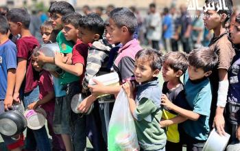 مواطنون ينتظرون في طوابير للحصول على طعام مجاني من تكية خيرية في مخيم النصيرات وسط قطاع غزة