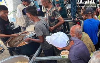 مئات المواطنين ينتظرون للحصول على طعام مجاني من تكية خيرية في مخيم النصيرات وسط قطاع غزة
