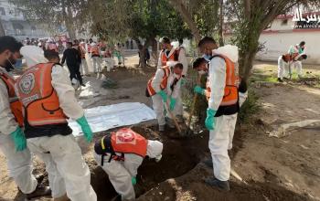 منقذون ومتطوعون يستخرجون جثامين ضحايا الحرب من مقبرة مؤقتة داخل مستشفى المعمدان في مدينة غزة