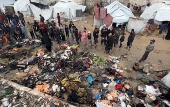 فلسطينيون يتفقدون بقايا خيمة بعد حريق ليلي في مخيم اليرموك بغزة