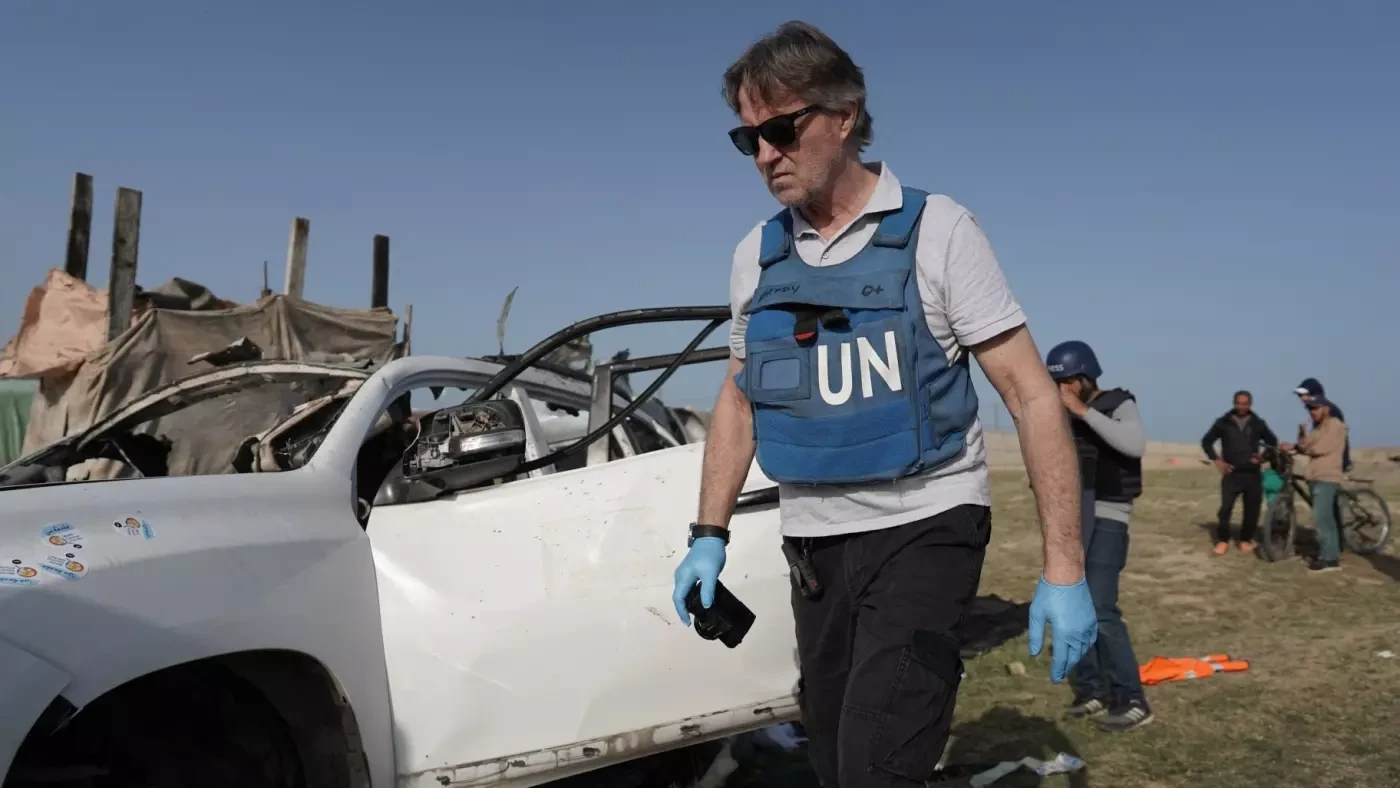 UN staff members inspect the carcass of a car used by US-based aid group World Central Kitchen, that was hit by an Israeli strike in Deir al-Balah, central Gaza on 2 April, 2024 (AFP).jpg.webp