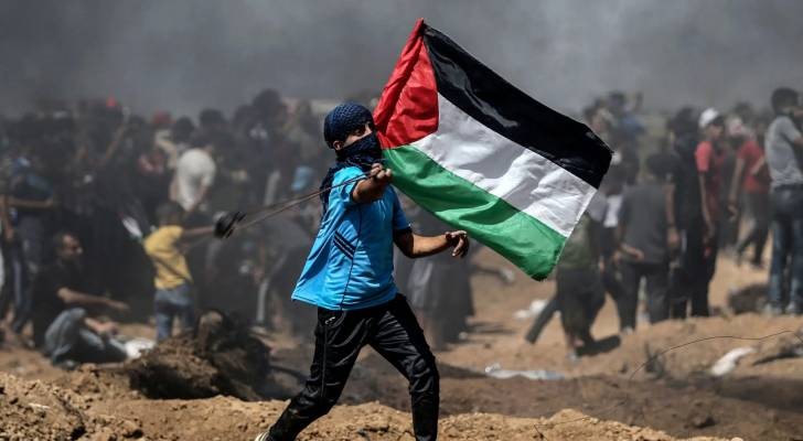 شاب فلسطيني يرفع علم فلسطين في مواجهات بالضفة الغربية