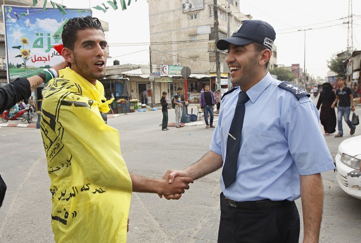 شرطي بغزة يصافح شاباً فلسطينياً
