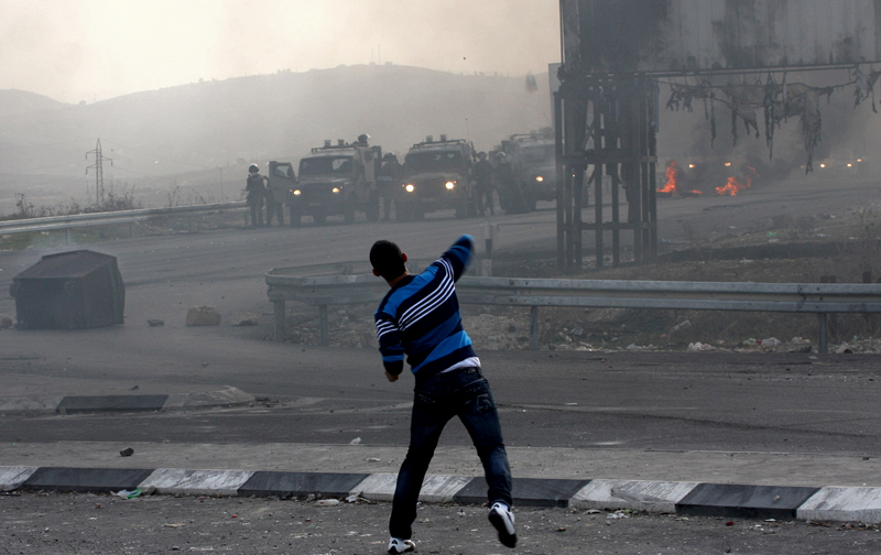شاب فلسطيني يرشق قوات الإحتلال بالحجارة