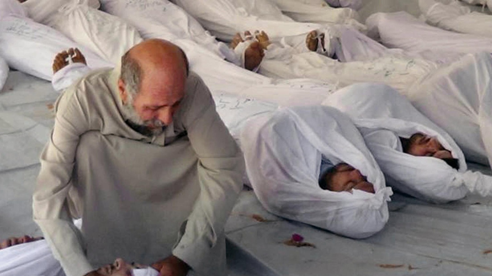 رجل سوري محاط بجثث ضحايا قصف بالغازات السامة على مدينة دوما بريف دمشق