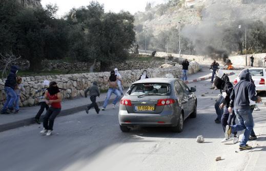  فتية فلسطينيون يلقون الحجارة تجاه سيارة مستوطنين